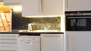 A modern kitchen with white cabinets, a black tiled backsplash, a Siemens dishwasher, and a Siemens oven. - Renovated 2-Room Ski-In/Ski-Out Unit, Sleeps 6, Near Shops & Services (Les Carroz d'Arâches)