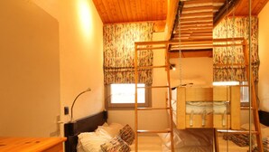 A compact room with bunk beds, a wooden dresser, and a window with patterned curtains. - Renovated 2-Room Ski-In/Ski-Out Unit, Sleeps 6, Near Shops & Services (Les Carroz d'Arâches)