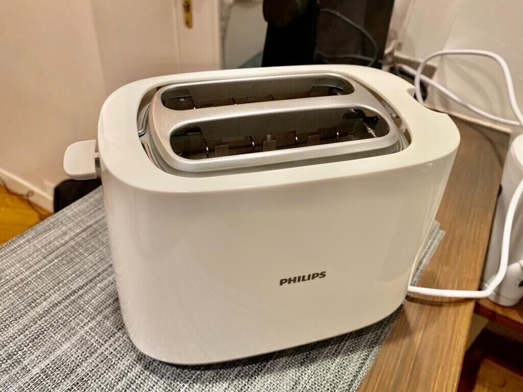 A white Philips toaster on a table with a gray cloth.