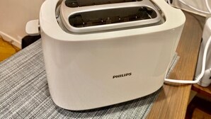 Uma torradeira Philips branca sobre uma mesa com um pano cinzento.
