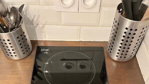 Uma cozinha com um fogão por indução preto, um painel de controle com vários botões e dois suportes de utensílios de aço inoxidável.