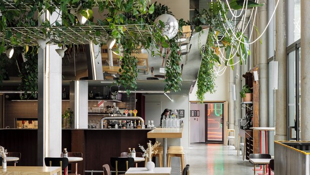 A modern restaurant with high ceilings, hanging plants, and a bar area. - The People Lyon  (Lyon)