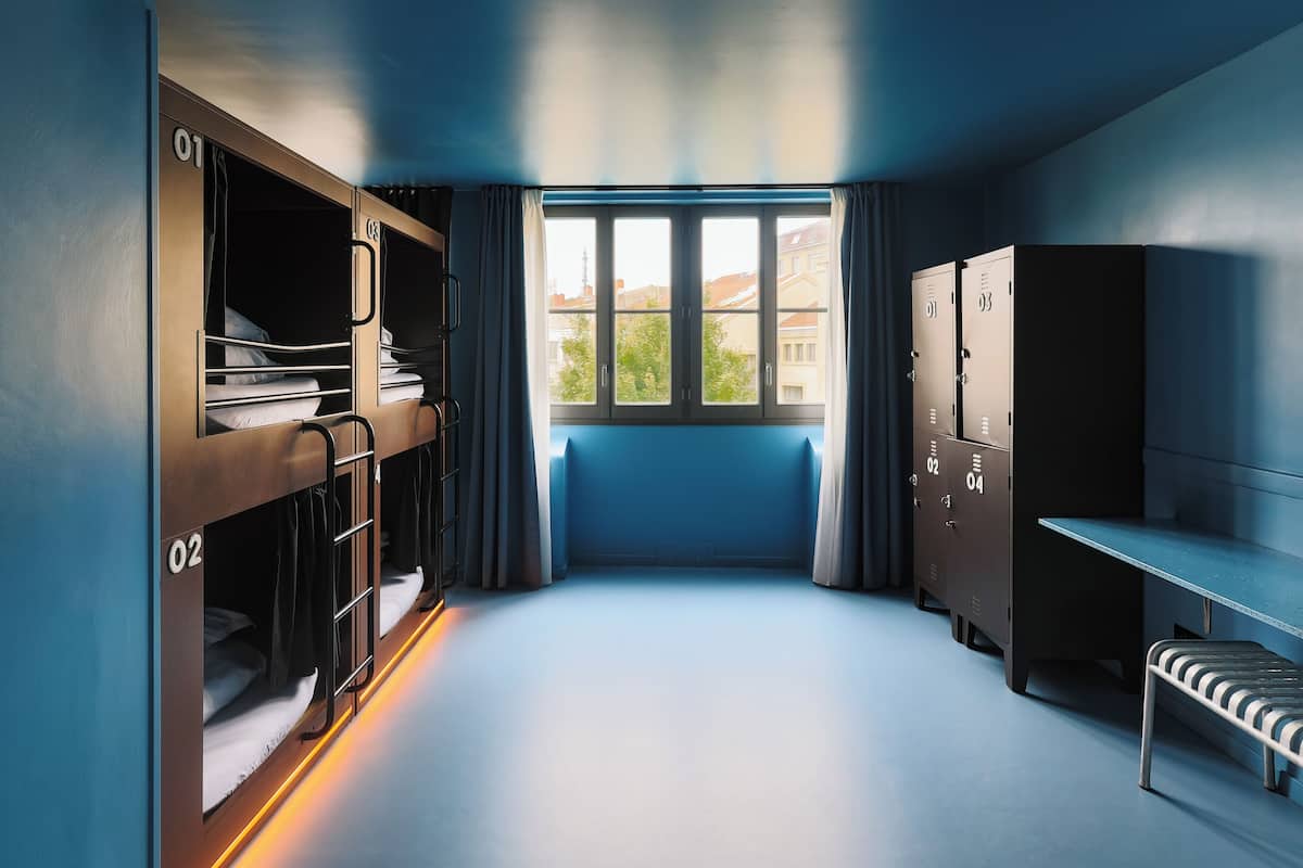 Ein Schlafsaalzimmer mit Etagenbetten, einem Schreibtisch und Schließfächern.