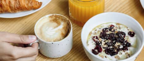 A breakfast setting with various food items and a glass of orange juice on a wooden table.