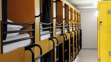 A row of bunk beds with metal railings and numbered compartments, indicating a dormitory-style room.