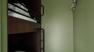 Habitación con literas, una escalera, un estante pequeño y un cabezal de ducha instalado en la pared.