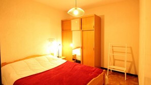 A bedroom with a bed, a wardrobe, a chair, and a lamp. - Studio for 6 people with renovated bathroom and parking, on the slopes (Les Carroz d'Arâches)