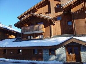 Een houten lodge met meerdere balkons en een stenen entree.
