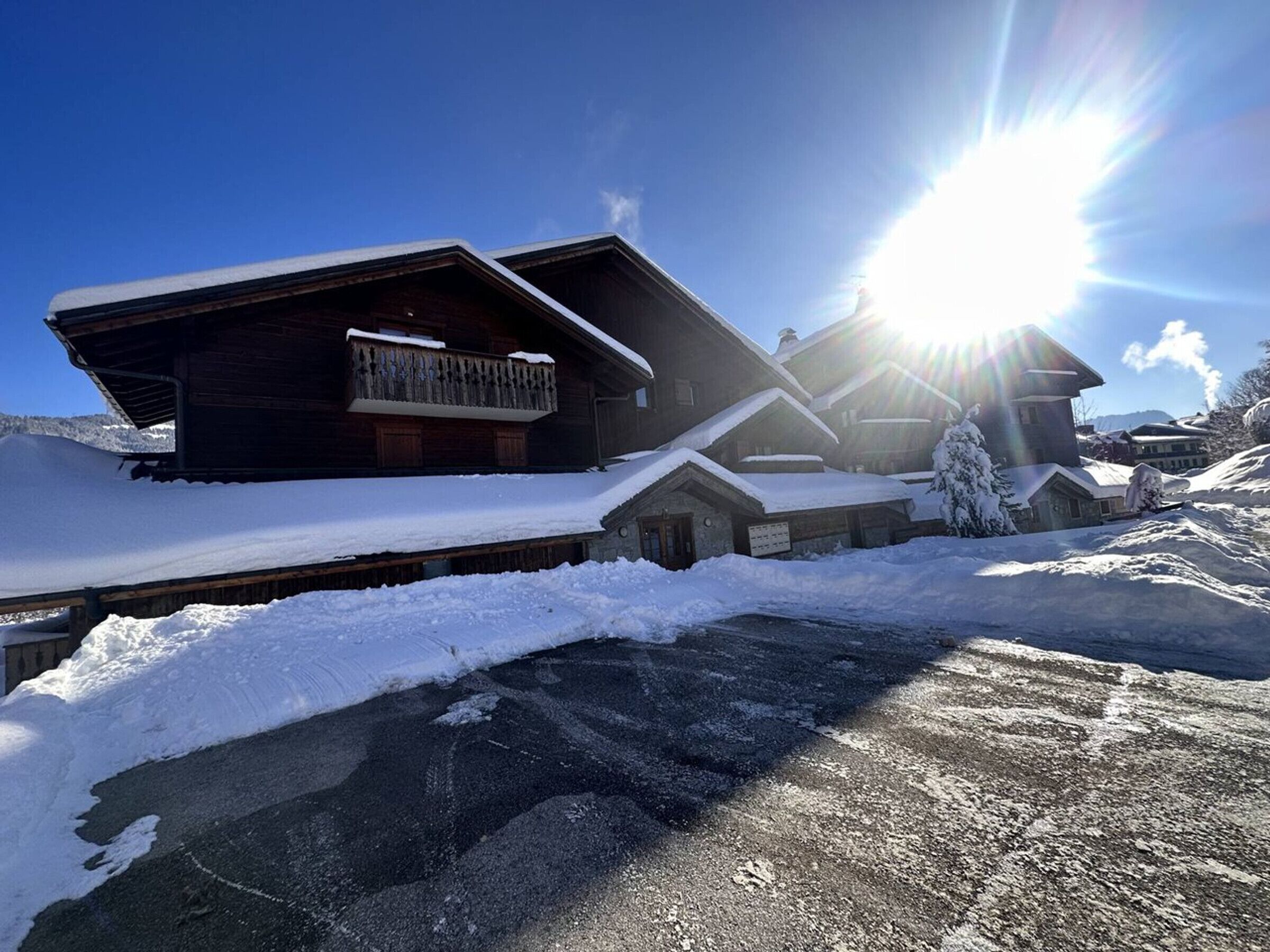 Un hilera de cabañas de madera con techos nevados y un cielo despejado.