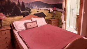 Un dormitorio con cama, mesita de noche, lámpara, cómoda de madera y zona de ducha.