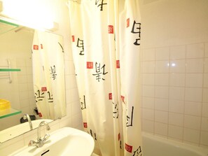 A bathroom with a sink, mirror, and white tiled walls. - Mezzanine studio for 5, at the foot of shops, 450m from slopes (Les Carroz d'Arâches)