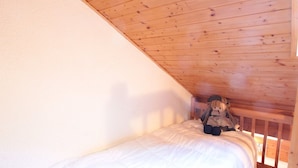 A single bed in a room with wooden ceiling beams and white walls. - Mezzanine studio for 5, at the foot of shops, 450m from slopes (Les Carroz d'Arâches)