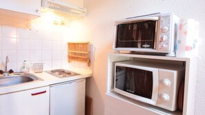 A compact kitchen with a sink, a stove, and two microwaves stacked on a white cabinet. - Mezzanine studio for 5, at the foot of shops, 450m from slopes (Les Carroz d'Arâches)