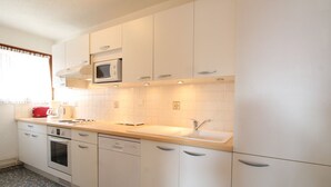 Une cuisine moderne avec des meubles blancs, un four à micro-ondes, un évier et un grille-pain.