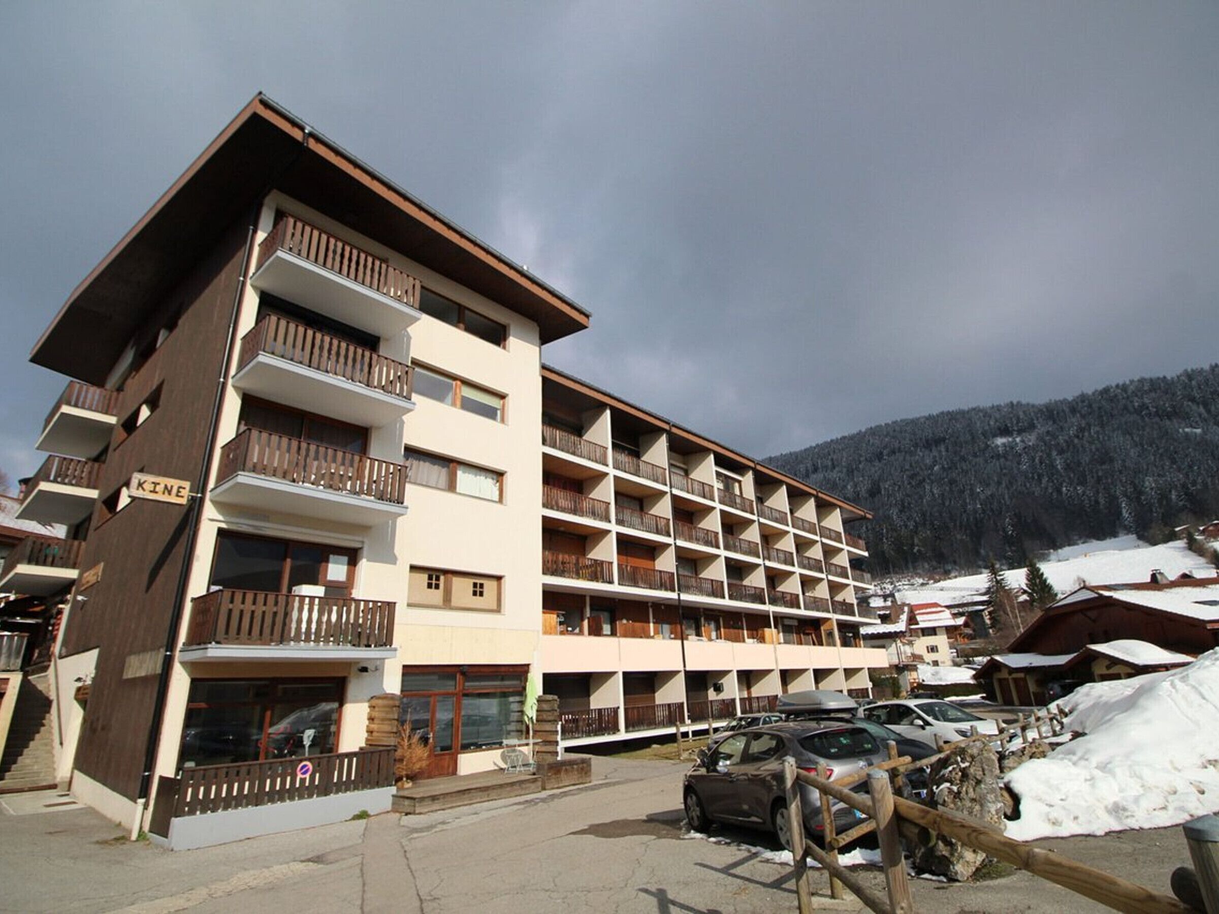 Un hôtel à plusieurs étages doté de balcons, avec une station de ski en toile de fond.
