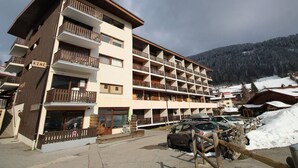 Un hôtel à plusieurs étages doté de balcons, avec une station de ski en toile de fond.