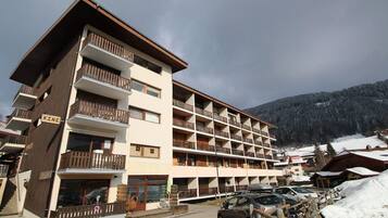 Un hôtel à plusieurs étages doté de balcons, avec une station de ski en toile de fond.