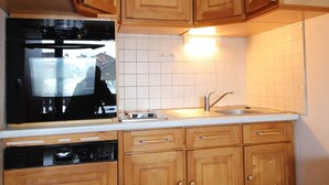 Eine Küche mit Holzausstattung, einem Edelstahlspülbecken und einem eingebauten Geschirrspüler.