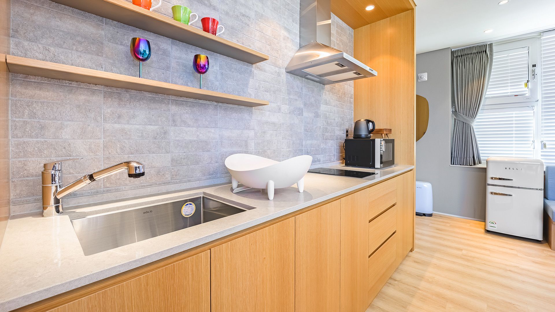 A modern kitchen with a built-in sink, wooden cabinets, a white countertop, and a stainless steel faucet.