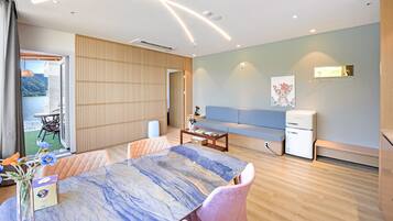 A modern living room with a dining table, sofa, and a small kitchenette.