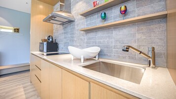 A modern kitchen with a built-in sink, a white bathtub, and a coffee machine.