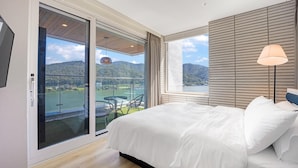 Ein Schlafzimmer mit einem großen Bett, Seeblick und Bergblick, sowie einem Balkon mit Tisch und Stühlen.