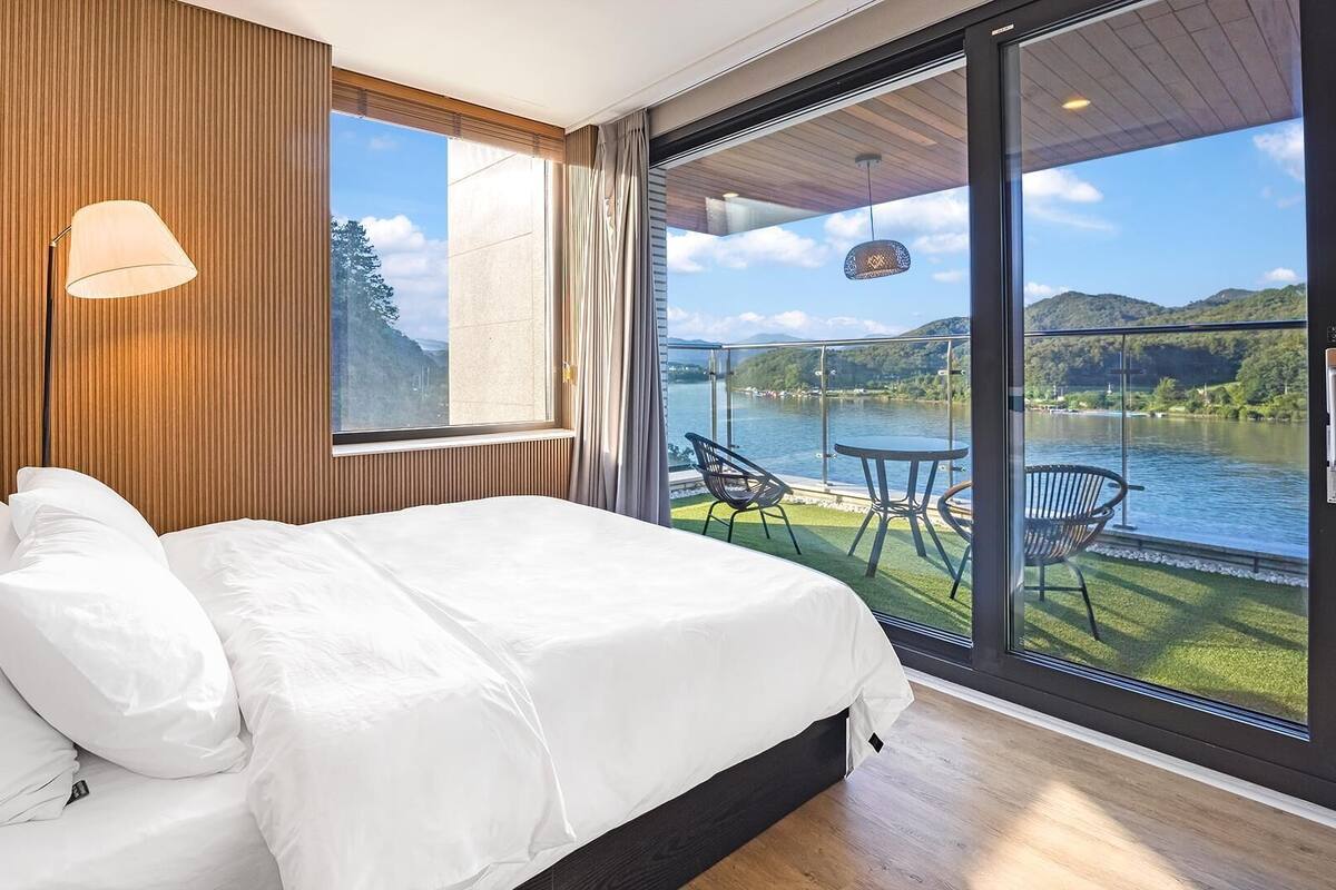Ein Schlafzimmer mit einem großen Bett, einem Fenster und einem Balkon mit Stühlen und einem Tisch.