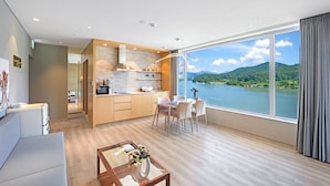 Eine moderne Küche mit Seeblick und Bergblick, ein Essbereich mit Tisch und Stühlen sowie ein Wohnbereich mit Sofa und Couchtisch.