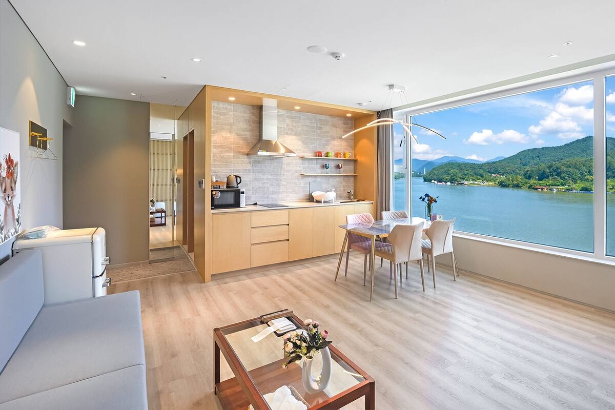 Eine moderne Küche mit Seeblick und Bergblick, ein Essbereich mit Tisch und Stühlen sowie ein Wohnbereich mit Sofa und Couchtisch.