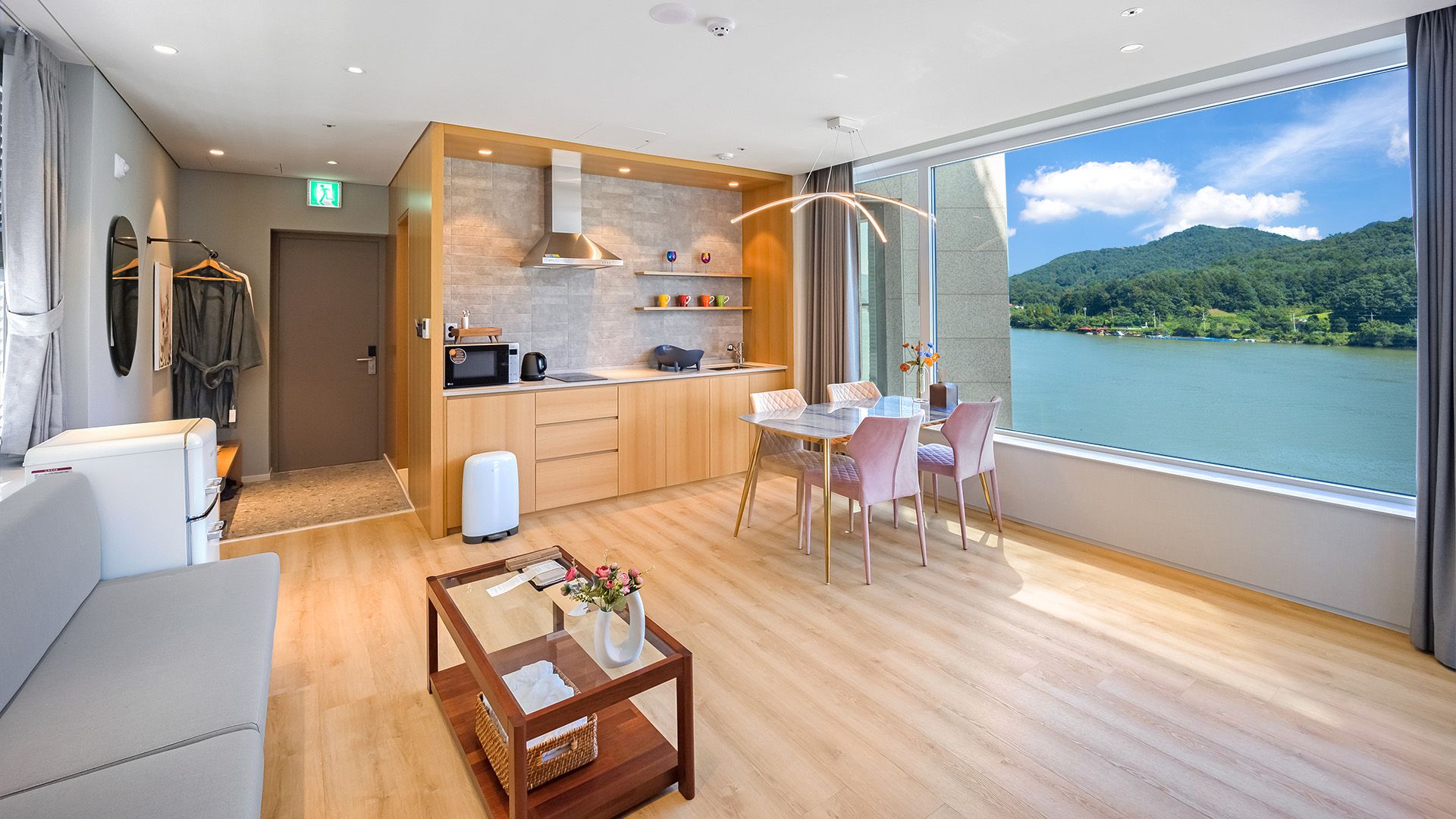 Una habitación de hotel moderna con cocina, comedor y un amplio ventanal con vista al lago.