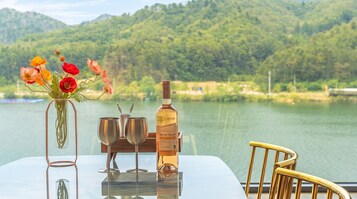 A table with a bottle of wine, two glasses, and a vase with flowers.