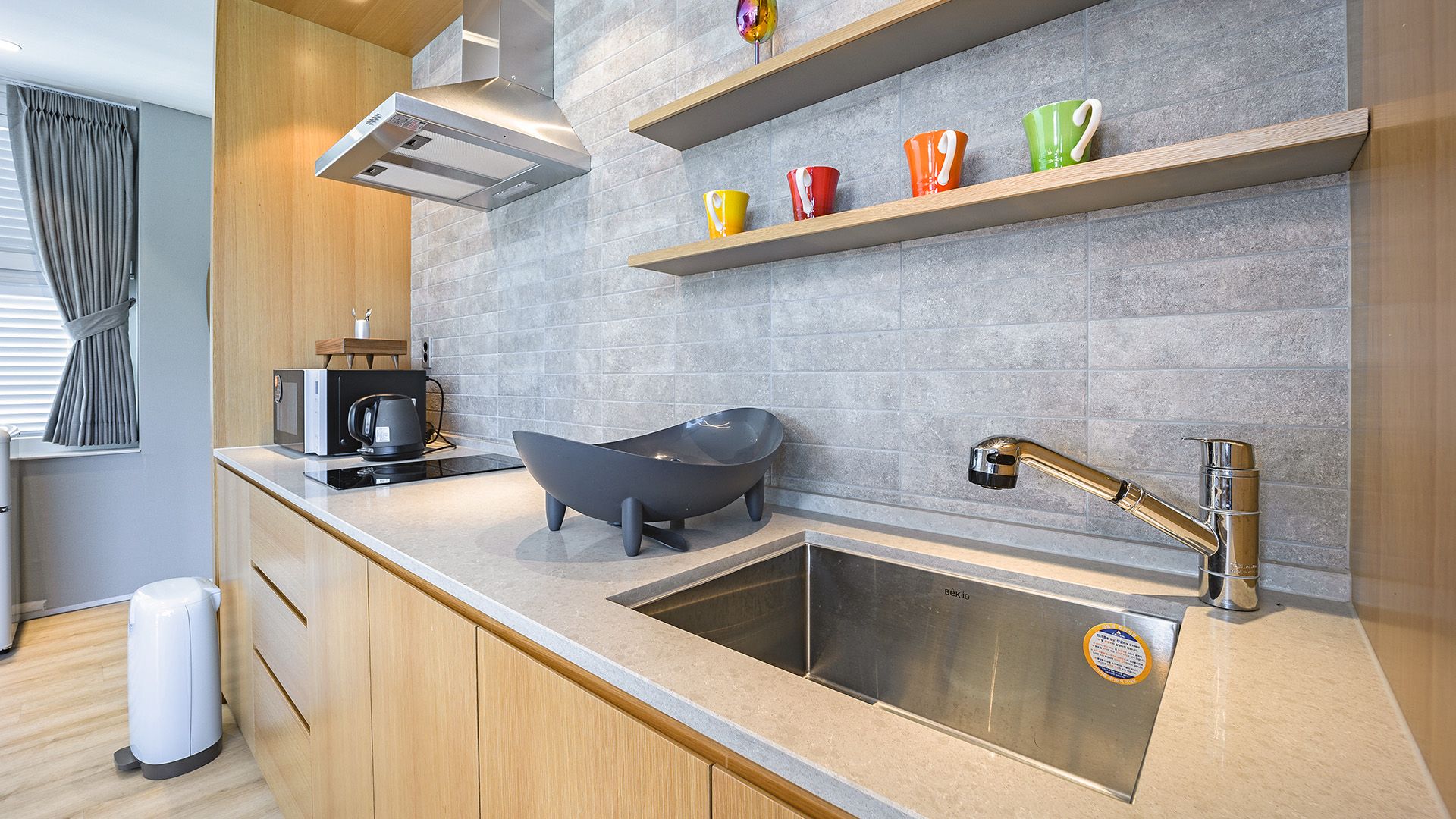 Eine moderne Küche mit Spüle, Wasserkocher und einer außergewöhnlichen schwarzen Badewanne.