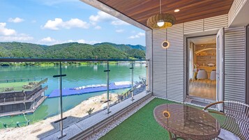 Un balcón con vistas a un río, una mesa, sillas y una puerta que da a una habitación con vistas.