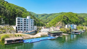 Ein Hotel am Flussufer mit Anlegesteg, Schwimmbad und Bergblick.