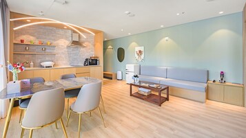 Una sala moderna con comedor, sofá y cocina equipada con microondas.