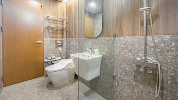 A bathroom with a toilet, bidet, sink, and shower.