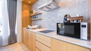 Une cuisine moderne dotée d’un four à micro-ondes encastré, de meubles en bois et d’une fenêtre avec des rideaux.