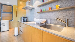 Une cuisine moderne dotée d’un plan de travail en granit, d’un évier en acier inoxydable et de meubles en bois.