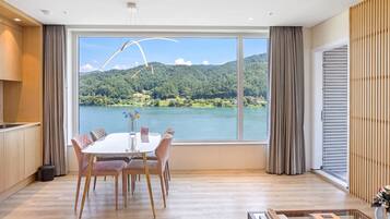 Un comedor moderno con un ventanal grande con vista a un lago y un bosque.
