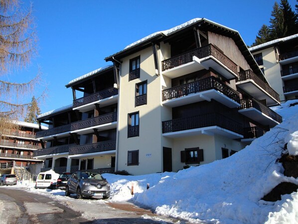 Ein mehrstöckiges Hotel mit Balkonen, einem Parkplatz und Schnee auf dem Boden.