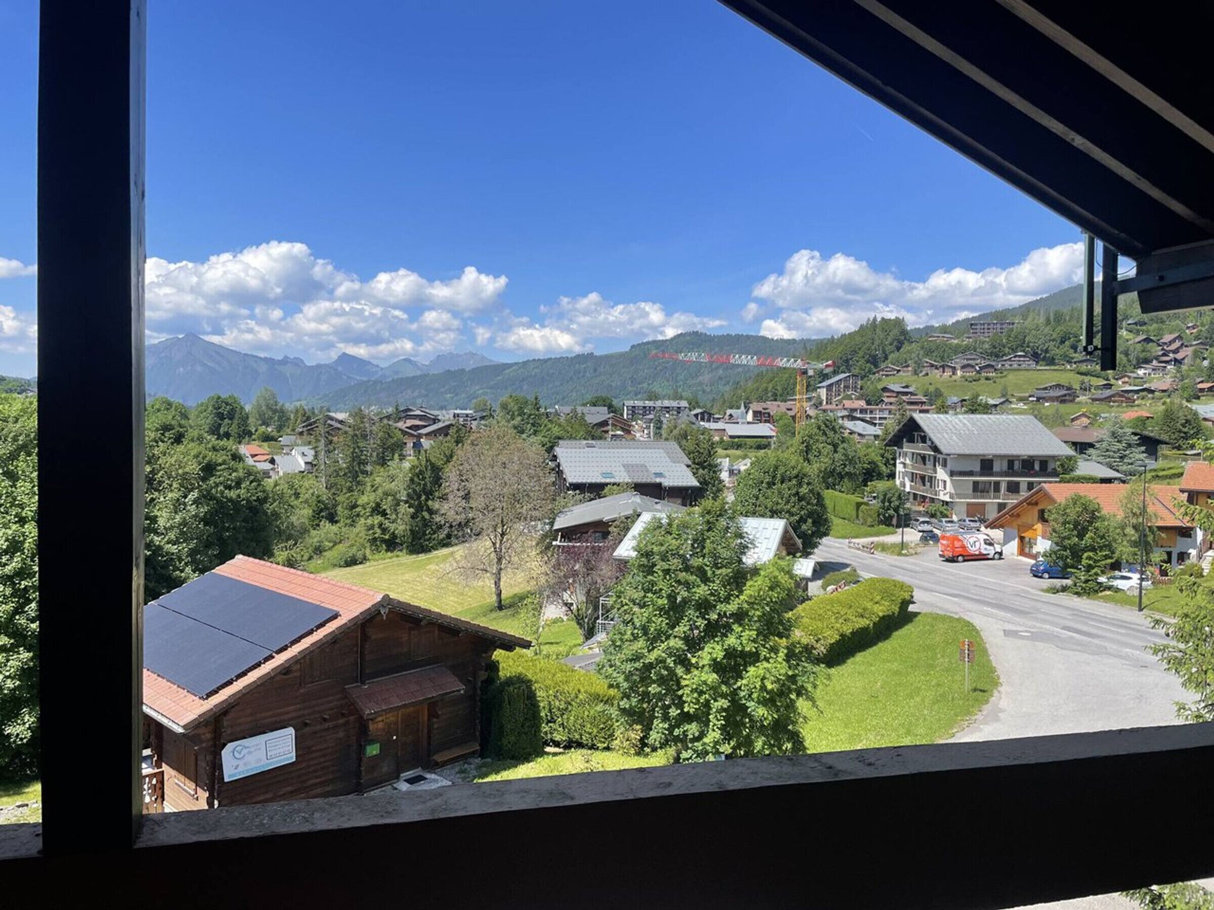 A view of a mountain town with houses, a road, and a mountain range in the background.