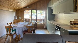 Un acogedor interior de cabaña con comedor, techo de madera y cocina con gabinetes grises.