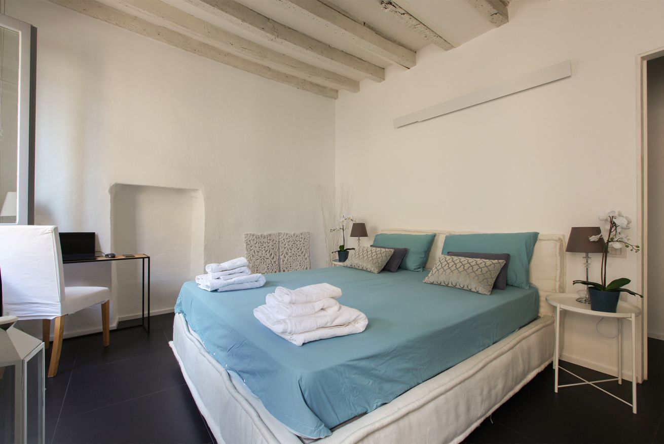 A bedroom with a bed, bedside tables, a desk, and a chair.