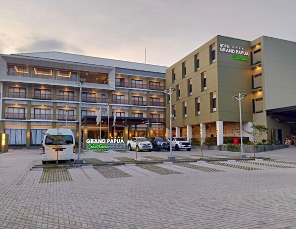 A hotel with multiple floors, a parking area, and a sign reading "HOTEL GRAND PAPUA." - Grand Papua Hotel Sentani (Sentani)