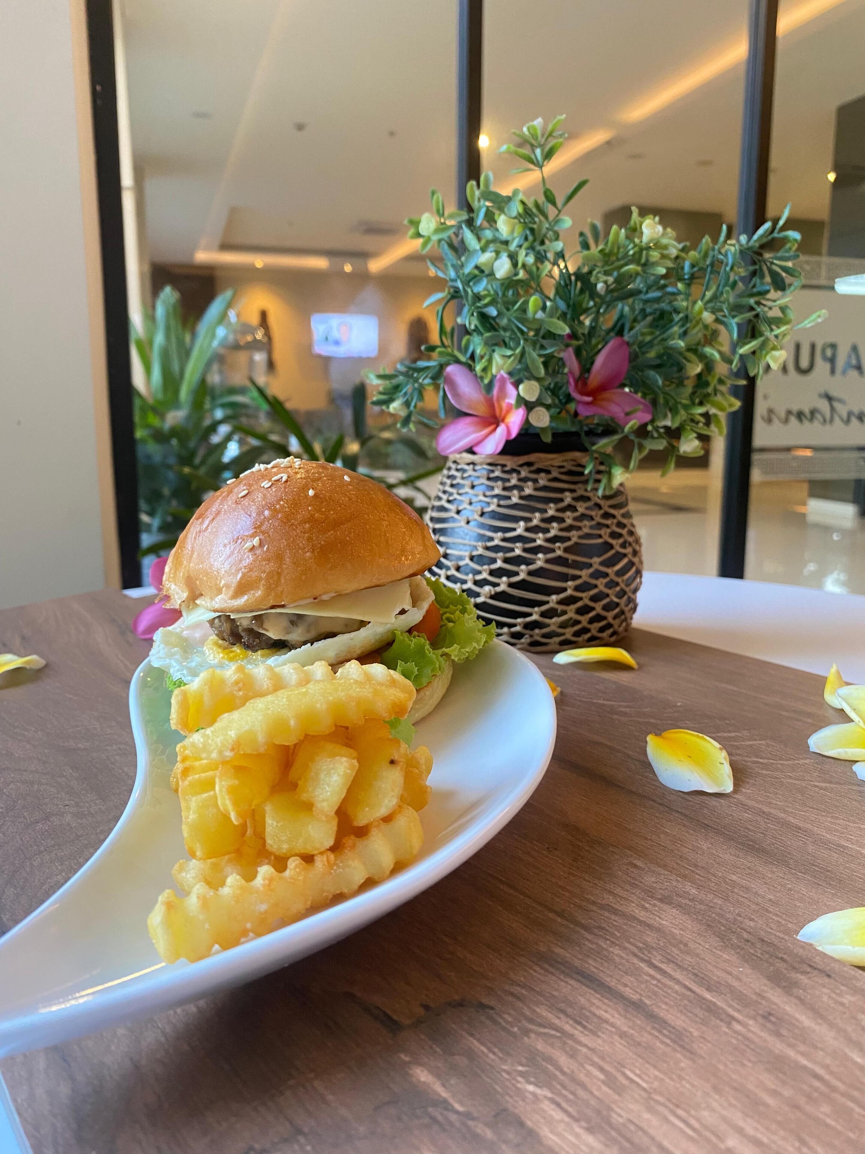 Une assiette avec un hamburger et des chips de pommes de terre, posée sur une table en bois.