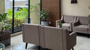 A modern interior with a large glass door leading to a balcony, a sofa, a small table, and a decorative wooden panel.