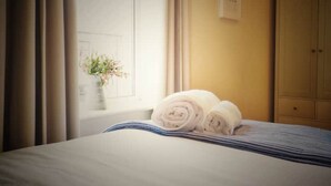 Ein Hotelzimmer mit Bett, Fenster mit Vorhängen, einer Blumenvase und einem Schild an der Wand.