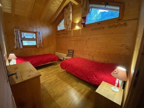 A cabin with two beds, wooden walls, and a window.