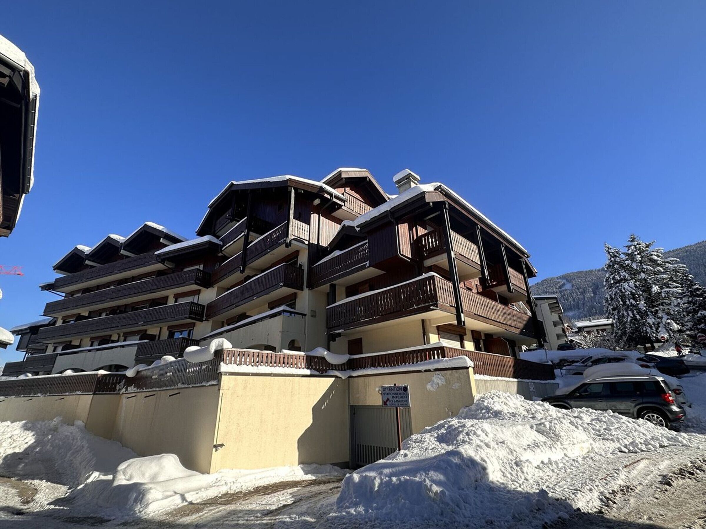 A multi-story hotel with balconies, a snow-covered ground, and a clear blue sky.