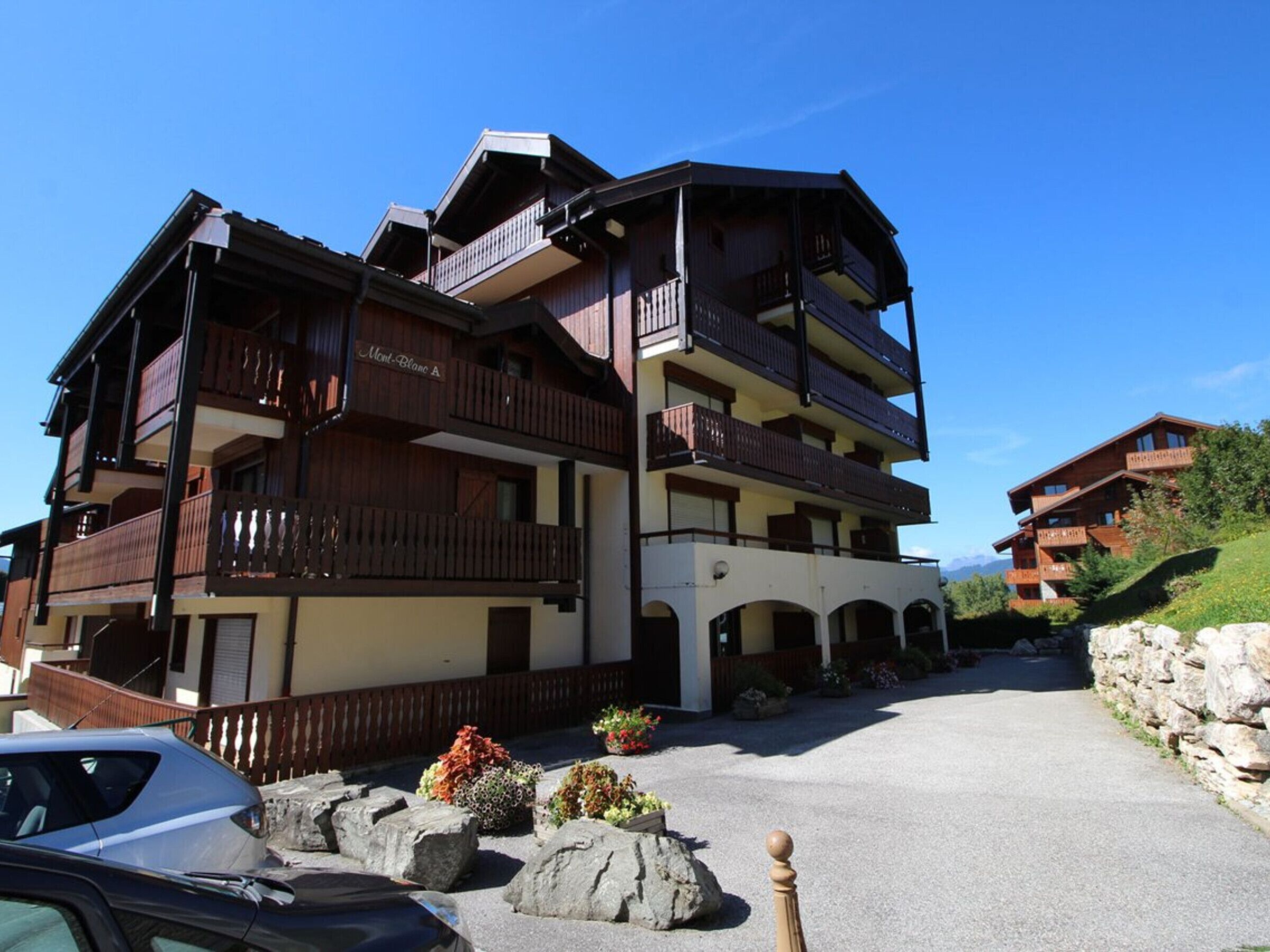 Un hotel de diversos pisos amb balcons i una zona d'aparcament.